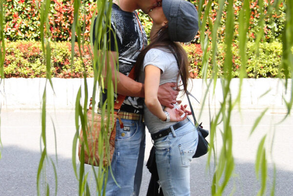 Couple kissing under weeping willow.