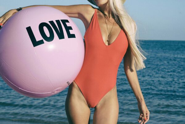 Woman in red swimsuit holding beach ball.
