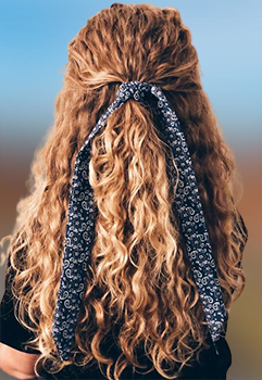 Here's an alt tag for the image: Long curly hair tied with ribbon.